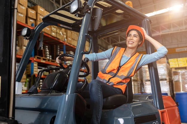 Heureuse femme travailleur entrepôt personnel conducteur de chariot élévateur heureux souriant aime travailler les asiatiques