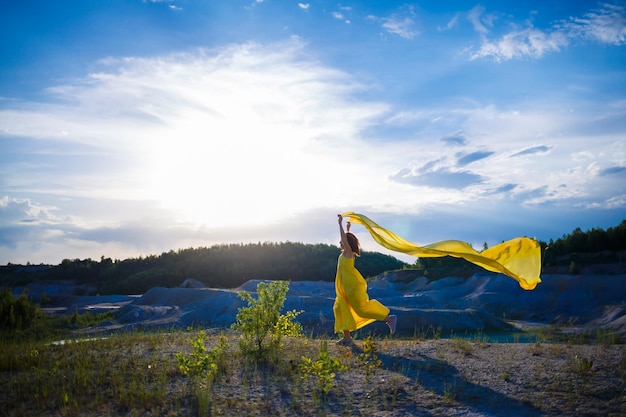 Heureuse femme ukrainienne courant dans la nature Dans une longue robe jaune Symbole de la liberté de l'Ukraine Femme patriote de l'Ukraine Liberté paix sans guerre mise au point sélective