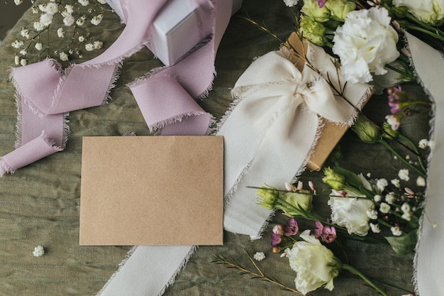 Heureuse fête des femmes et concept de fête des mères Cadeau de carte vide élégant et belles fleurs avec des rubans sur fond de tissu vert plat poser Modèle de carte de voeux espace pour le texte