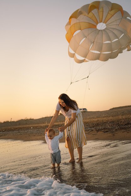 Heureuse fête des mères Belle mère et bébé jouent sur la plage Maman et son enfant profitant ensemble du coucher du soleil Une mère célibataire aimante embrasse un petit fils mignon