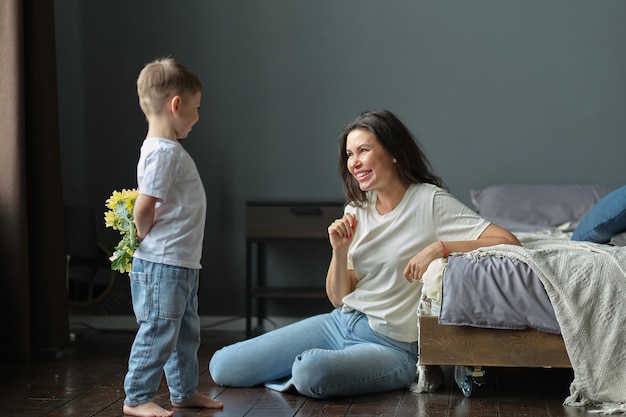 Heureuse fête des mères, le fils de l'enfant félicite sa mère en vacances et lui donne des fleurs pour la féliciter pour la fête des mères pendant les vacances à la maison