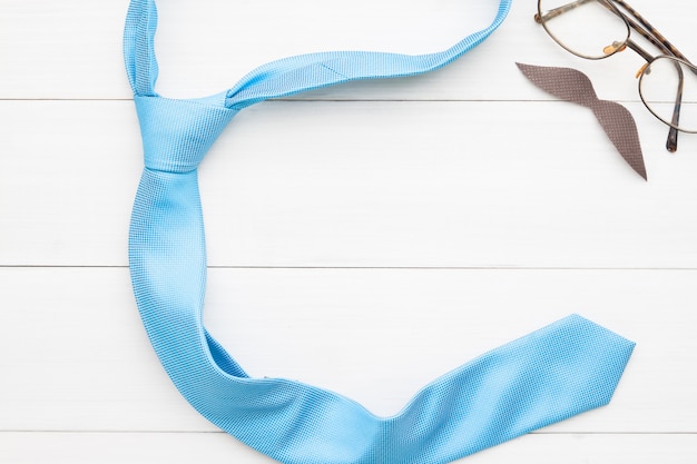 Heureuse fête des pères, lunettes, signe de moustache et cravate sur fond en bois blanc