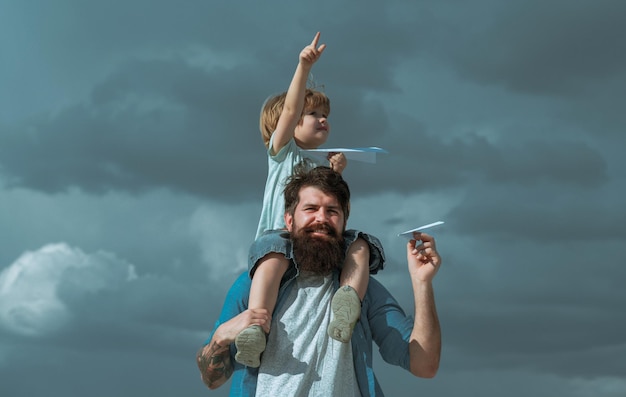 Heureuse fête des pères papa et fils jouent sur fond de ciel l'enfant est assis sur les épaules de son père