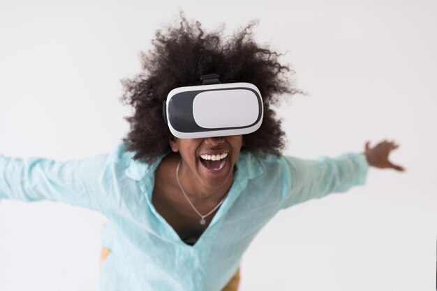 Heureuse fille afro-américaine acquérir de l'expérience en utilisant des lunettes de casque VR de réalité virtuelle, isolée sur fond blanc