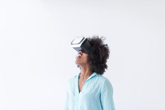 Heureuse fille afro-américaine acquérir de l'expérience en utilisant des lunettes de casque VR de réalité virtuelle, isolée sur fond blanc