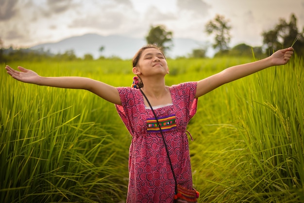 Heureuse fille asiatique, levant les bras dans le champ de riz vert, campagne de la Thaïlande au coucher du soleil