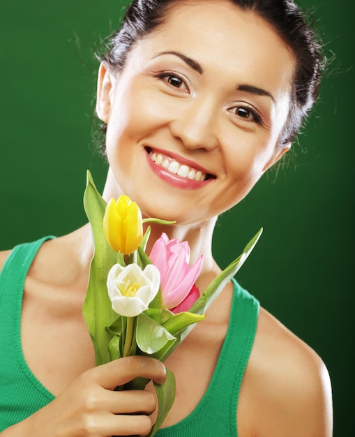 Heureuse fille asiatique avec des tulipes se bouchent