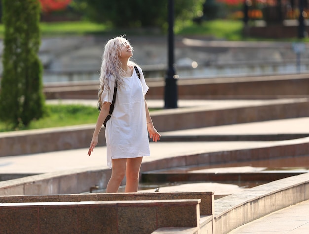 heureuse fille blonde en robe blanche