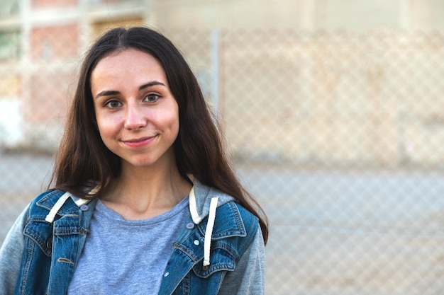 Heureuse fille caucasienne aux cheveux longs regardant la caméra à l'extérieur de l'espace de copie