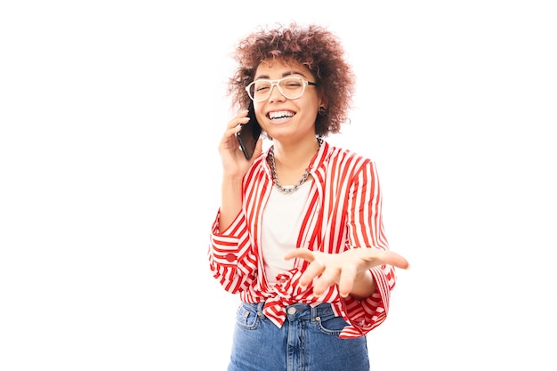 Heureuse fille caucasienne bouclée souriante parlant smartphone isolé sur fond de studio blanc