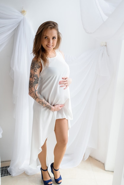 Heureuse fille enceinte en robe blanche.