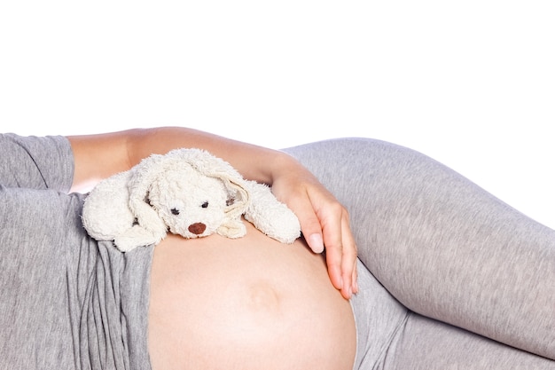 Heureuse fille enceinte se trouve sur le mur blanc