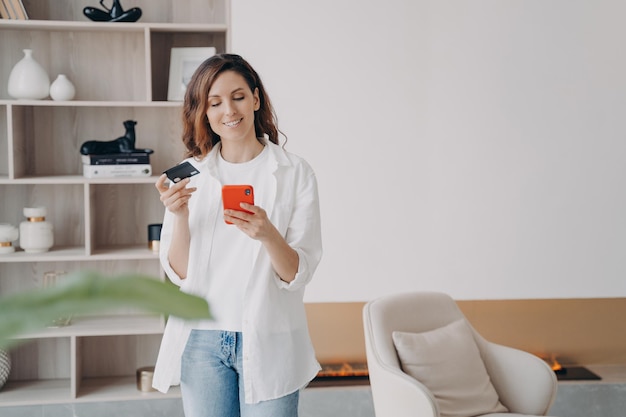 Heureuse fille espagnole tient une carte de crédit et un téléphone Achat d'économies d'argent en ligne et remise