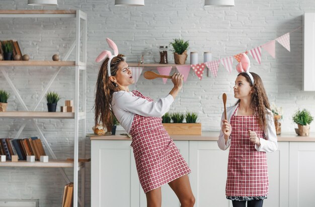 Heureuse fille et maman cuisinent et s'amusent dans la cuisine à la maison. Vacances en famille et unité.