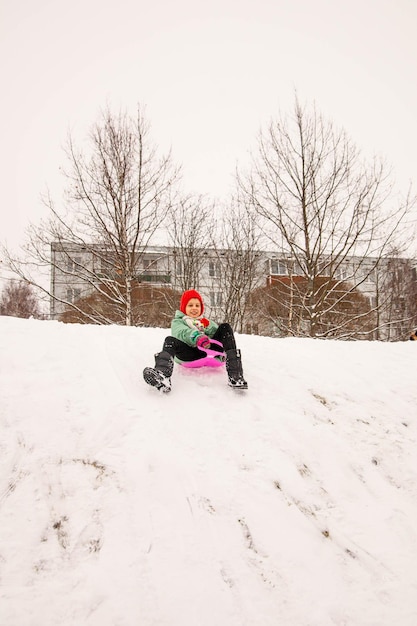 Heureuse fille de neuf ans descendant une glissade de glace sur un traîneau