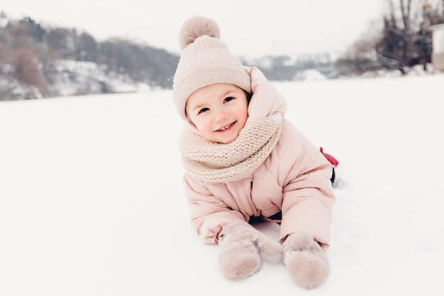 Heureuse fille riante portant une écharpe de veste rose et un chapeau jouant dans une belle promenade d'hiver enneigée La fille aime le jour glacial d'hiver Jouer avec la neige pendant les vacances d'hiver Concept de vacances d'hiver