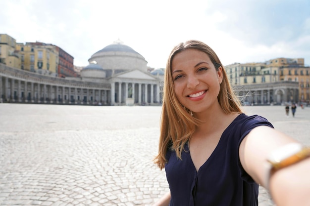 Heureuse fille souriante prenant une photo de selfie à Naples avec la place Piazza del Plebiscito en arrière-plan Naples Italie