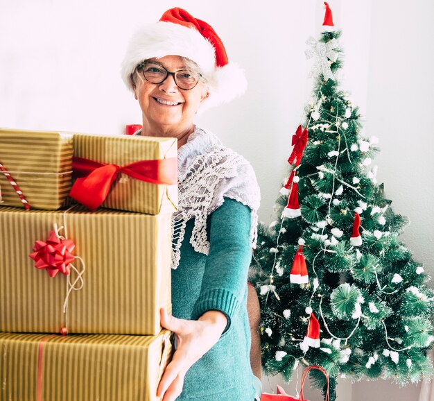 heureuse grand-mère à la maison tenant de nombreux cadeaux de Noël pour la famille attachés avec un arc rouge