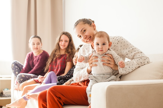 Heureuse grande famille de frères et sœurs assis sur le canapé dans une salle blanche