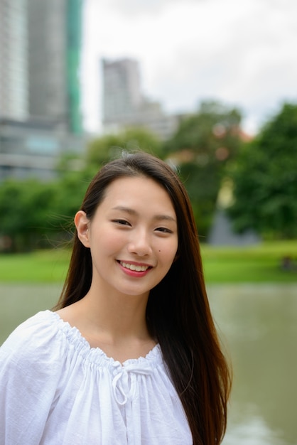 Heureuse jeune belle adolescente asiatique dans le parc