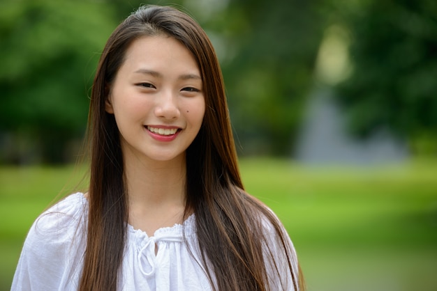 Heureuse jeune belle adolescente asiatique dans le parc