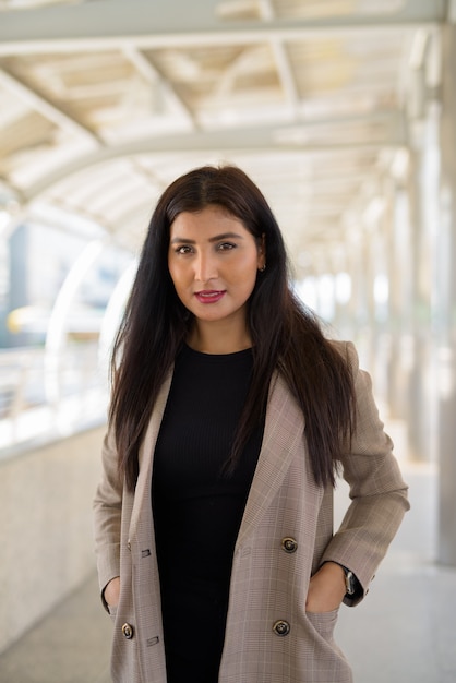 Heureuse jeune belle femme d'affaires indienne souriant à la passerelle dans la ville