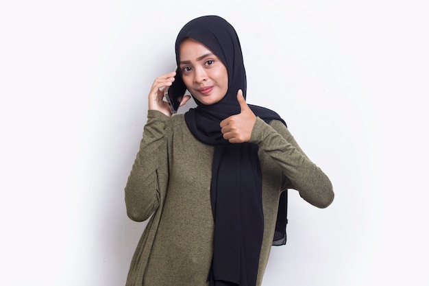 Heureuse jeune belle femme musulmane asiatique utilisant un téléphone portable isolé sur fond blanc