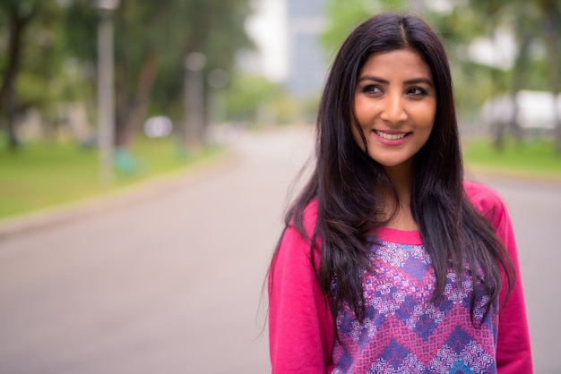 Heureuse jeune belle femme persane pensant au parc