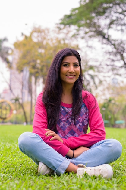 Heureuse jeune belle femme persane se détendre dans le parc