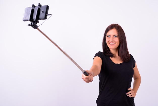 Heureuse jeune belle femme prenant selfie avec téléphone sur bâton selfie