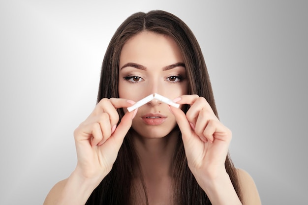 Heureuse jeune belle femme tenant une cigarette cassée pour arrêter de fumer concept