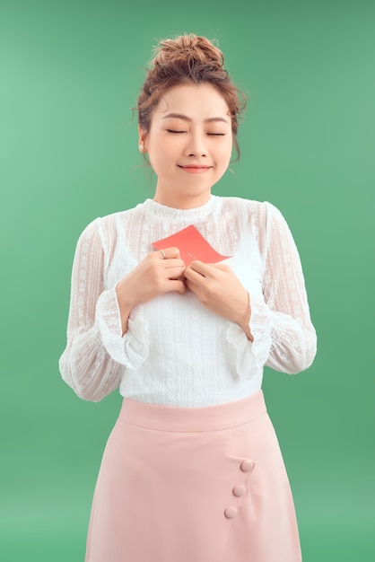 Heureuse jeune belle fille asiatique avec une carte postale d'amour valentines sur fond vert