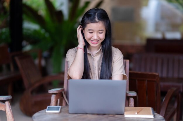 Photo heureuse de jeune étudiante adolescente asiatique qui utilise un ordinateur portable pour écrire sur un ordinateur.