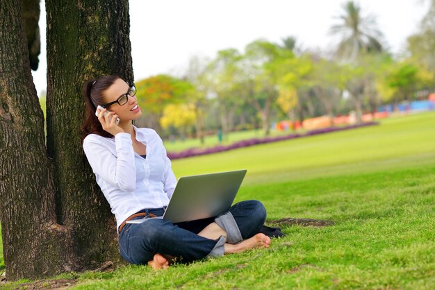 heureuse jeune étudiante femme avec ordinateur portable dans l'étude du parc de la ville