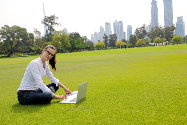 heureuse jeune étudiante femme avec ordinateur portable dans l'étude du parc de la ville