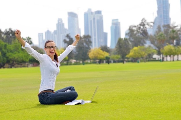 heureuse jeune étudiante femme avec ordinateur portable dans l'étude du parc de la ville