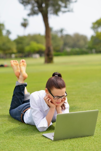 heureuse jeune étudiante femme avec ordinateur portable dans l'étude du parc de la ville