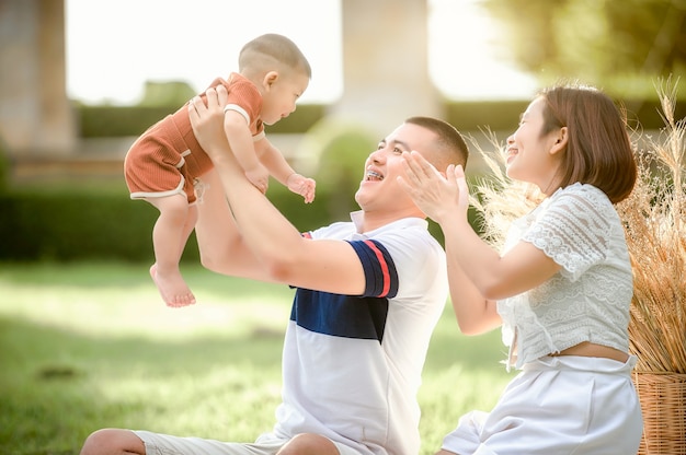 Heureuse jeune famille asiatique passant du temps en plein air pendant les vacances d'été. Une jeune famille heureuse passe du temps en plein air dans le jardin pendant les vacances d'été. Famille heureuse, assurance-vie, concept de stabilité dans la vie.