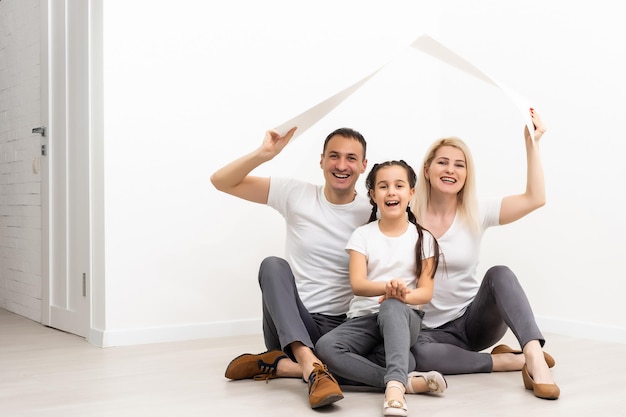 heureuse jeune famille assise sur le sol avec concept de maison.