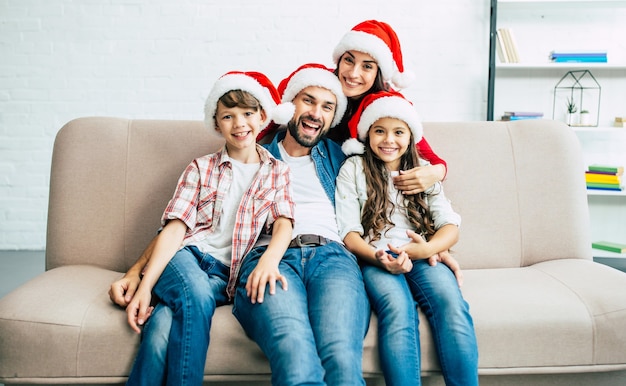Heureuse jeune famille en chapeaux rouges de Santa, passer du temps dans le salon