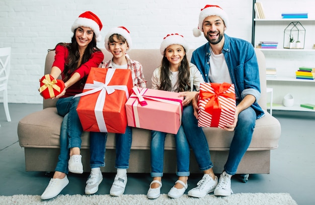 Heureuse jeune famille en chapeaux rouges de Santa, passer du temps dans le salon