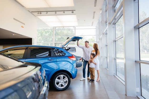 Heureuse jeune famille choisit et achète une nouvelle voiture chez un concessionnaire automobile