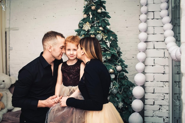 Heureuse jeune famille dans des vêtements élégants au moment de Noël