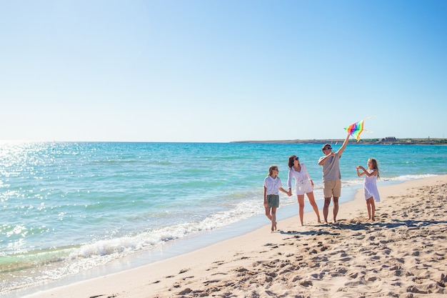 Heureuse jeune famille avec deux enfants avec un cerf-volant sur la plage