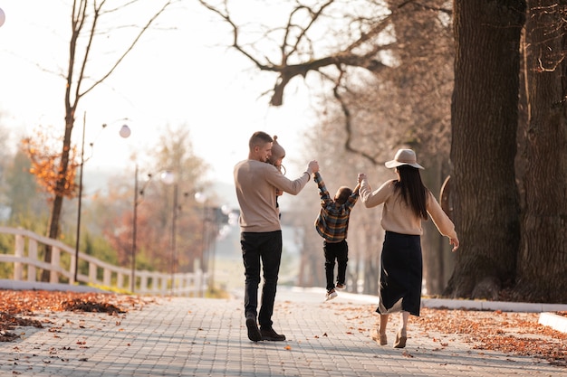 Heureuse jeune famille avec deux petits enfants marchant et s'amusant dans le parc d'automne aux beaux jours