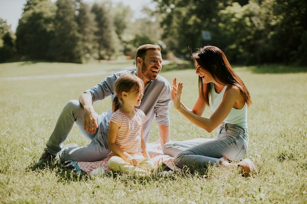 Heureuse jeune famille avec une jolie petite fille s'amusant dans le parc par une journée ensoleillée