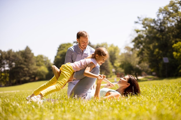 Heureuse jeune famille avec une jolie petite fille s'amusant dans le parc par une journée ensoleillée