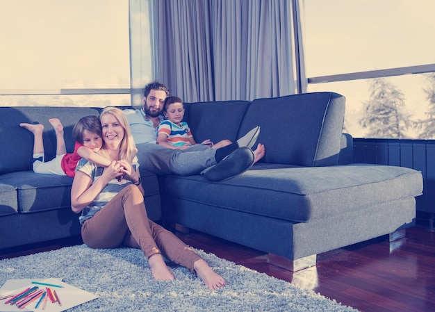 Heureuse jeune famille jouant ensemble à la maison sur le sol à l'aide d'une tablette et d'un ensemble de dessins pour enfants