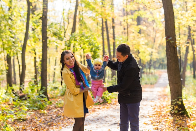 Heureuse jeune famille avec leur fille, passer du temps en plein air dans le parc de l'automne