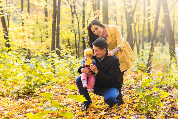 Heureuse jeune famille avec leur fille, passer du temps en plein air dans le parc de l'automne